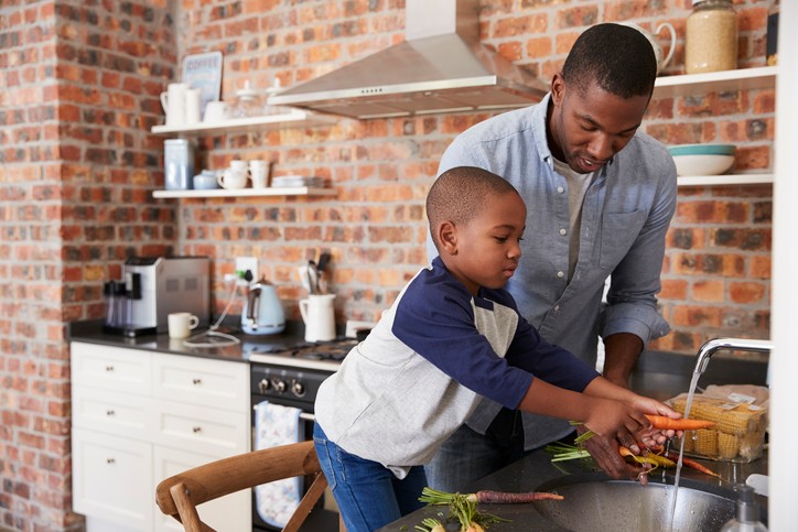 Man washing veggies with son