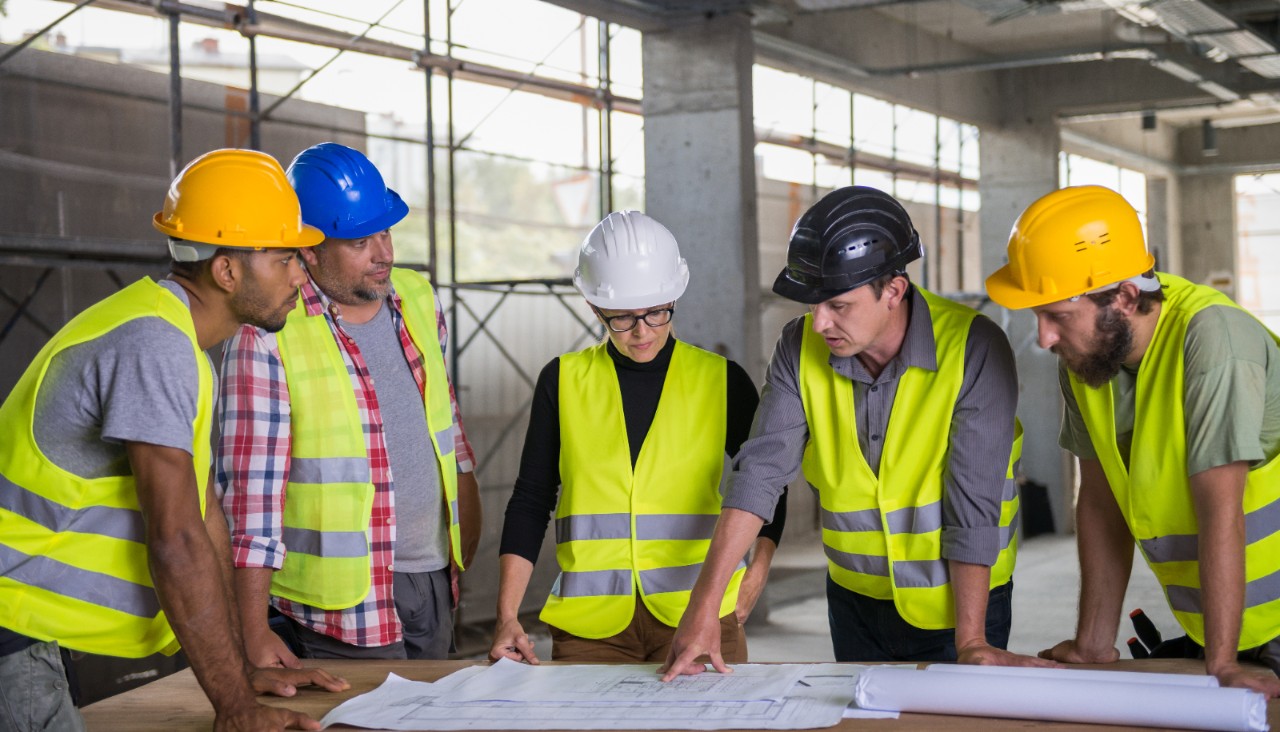 Builders standing and reviewing a construction site plan